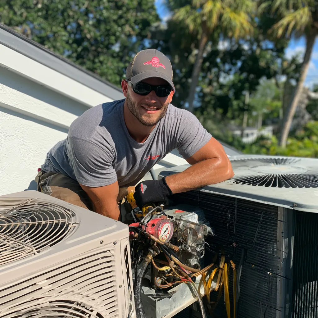 Smiling HVAC technician in sunglasses and work gloves leaning on an outdoor condenser with gauges connected